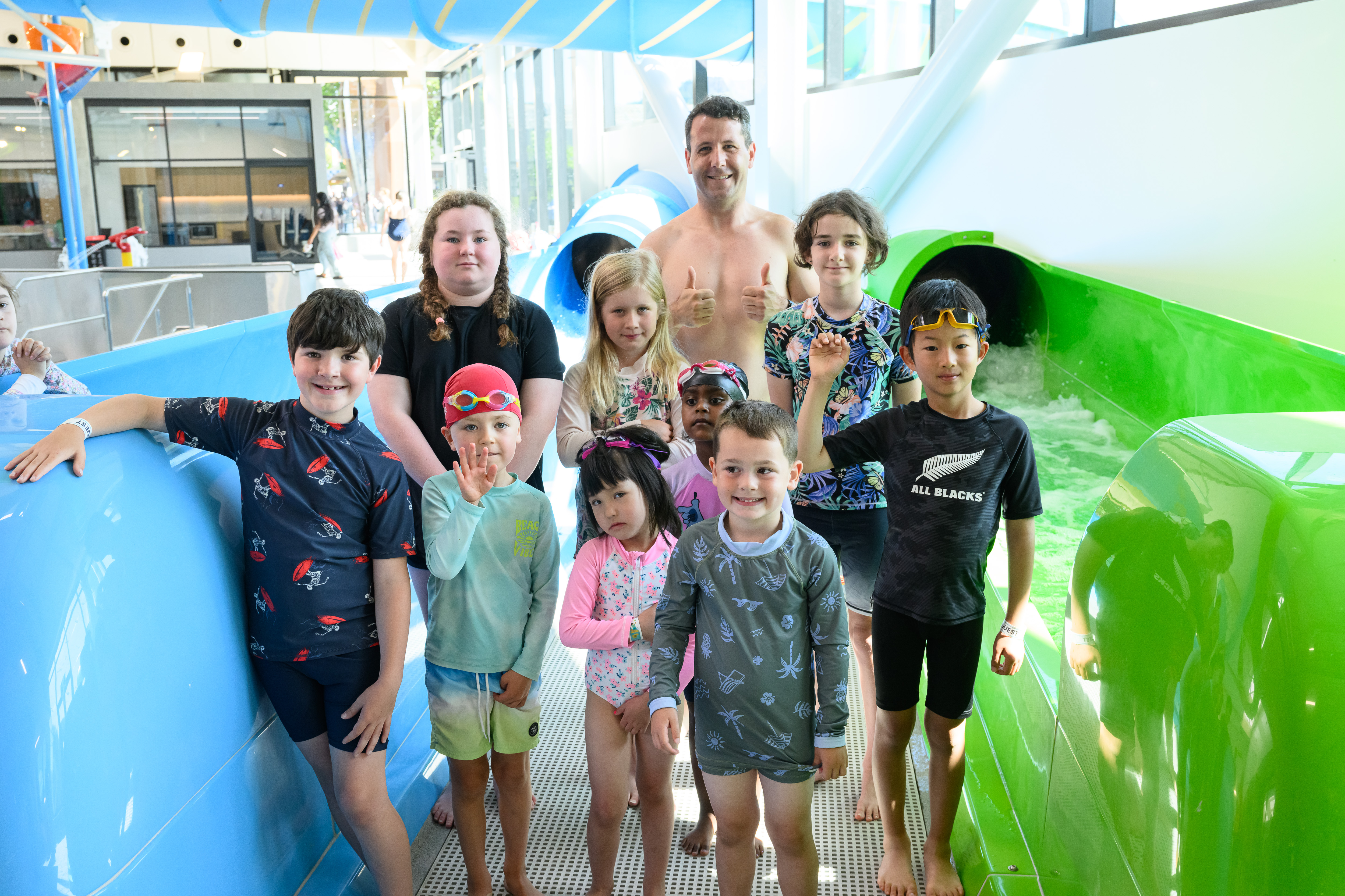 Children in swimming gear standing next to the zoom tube with the Mayor